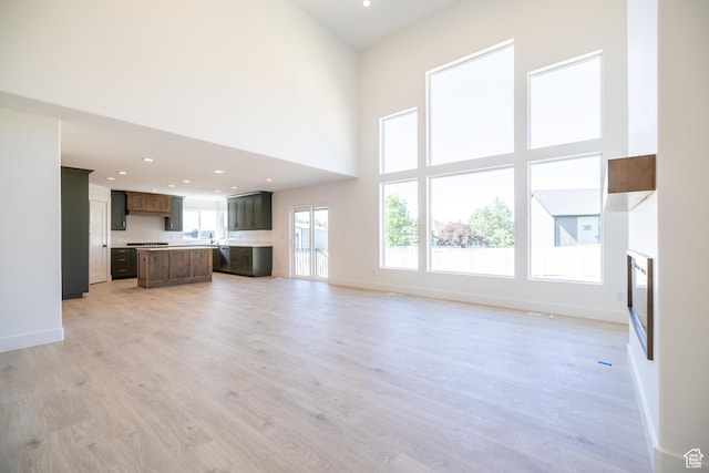 361 E Ventura Blvd, Tooele, UT 84074 - unfurnished living room with light wood-style floors, a towering ceiling, and recessed lighting
