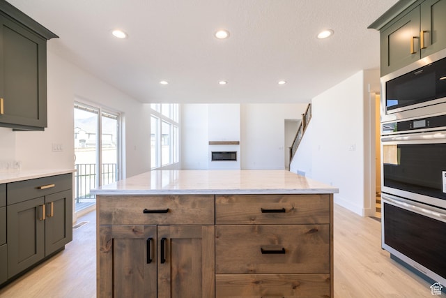 361 E Ventura Blvd, Tooele, UT 84074 - kitchen featuring appliances with stainless steel finishes, light wood-type flooring, recessed lighting, light stone countertops, and a fireplace