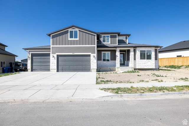361 E Ventura Blvd, Tooele, UT 84074 - view of front of home with an attached garage, concrete driveway, stone siding, covered porch, and board and batten siding