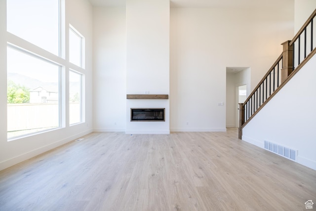 361 E Ventura Blvd, Tooele, UT 84074 - unfurnished living room featuring a high ceiling, light wood finished floors, stairway, and a glass covered fireplace