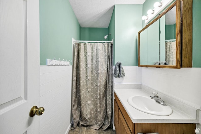 345 E 2475 N, North Logan, UT 84341 - full bathroom featuring vanity, a wainscoted wall, a textured ceiling, curtained shower, and tile walls