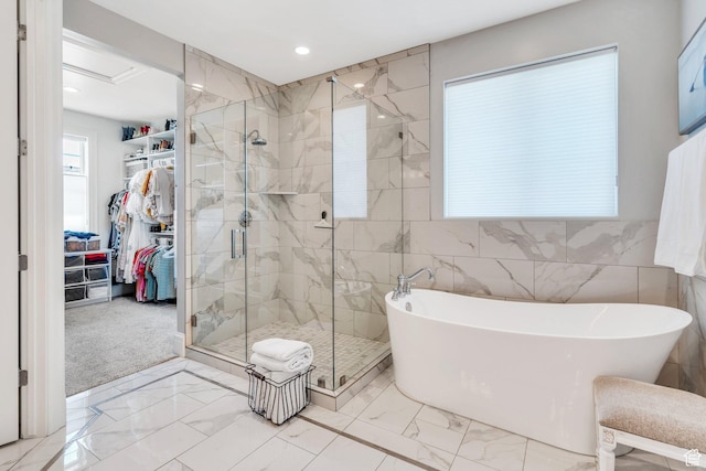 953 E 1000 N, American Fork, UT 84003 - full bathroom featuring a soaking tub, marble look tile flooring, a stall shower, a walk in closet, and tile walls