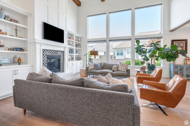 953 E 1000 N, American Fork, UT 84003 - living area featuring light wood-type flooring, plenty of natural light, a tile fireplace, a towering ceiling, and built in features