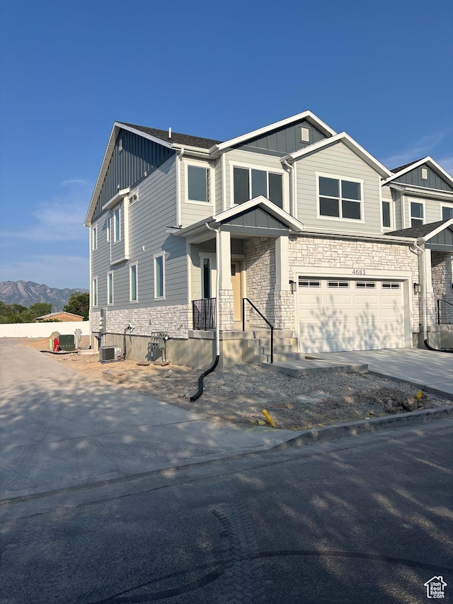 4683 S Roger View Ln W Unit 7, West Valley City, UT 84120 - view of front of property featuring board and batten siding, a garage, stone siding, concrete driveway, and a mountain view