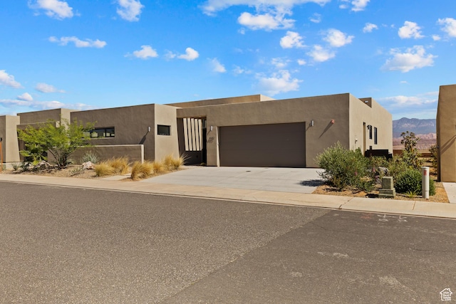 4982 W 3175 S, Hurricane, UT 84737 - pueblo-style house with a garage, concrete driveway, stucco siding, and a mountain view