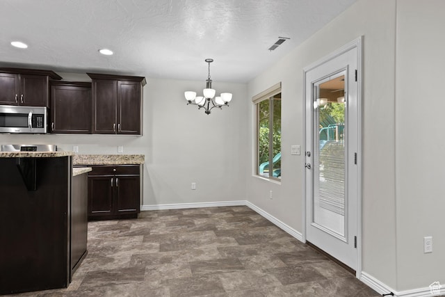 3342 S 240 W, Washington, UT 84780 - kitchen with stainless steel microwave, a chandelier, dark brown cabinets, decorative light fixtures, and light stone countertops