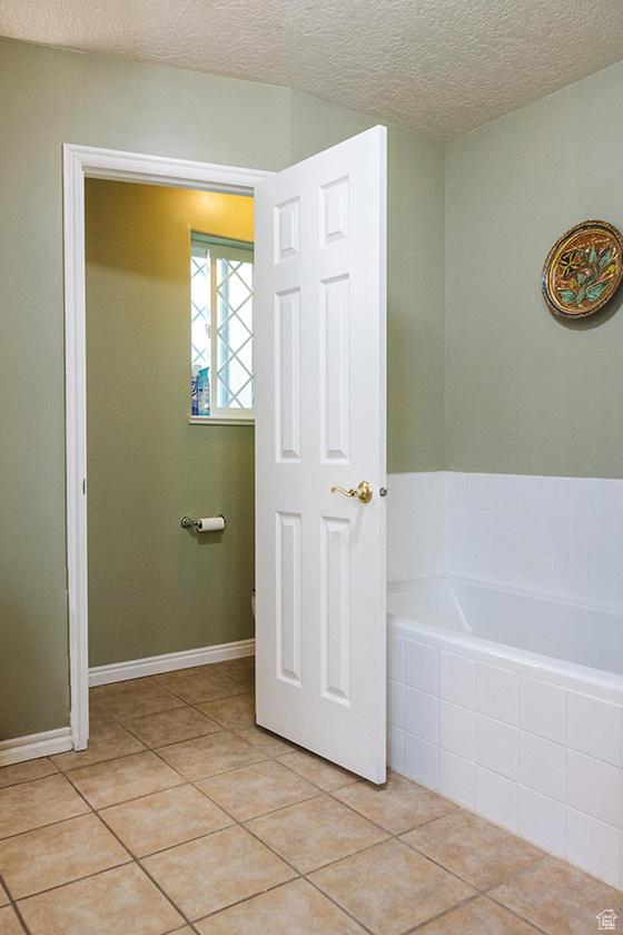 435 W Cobblestone Dr, Providence, UT 84332 - bathroom featuring a garden tub, tile patterned flooring, and a textured ceiling