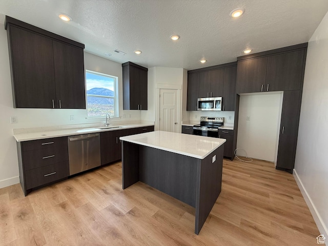 3298 S 1000 W, Nibley, UT 84321 - kitchen with appliances with stainless steel finishes, light countertops, a kitchen island, light wood-style flooring, and a textured ceiling