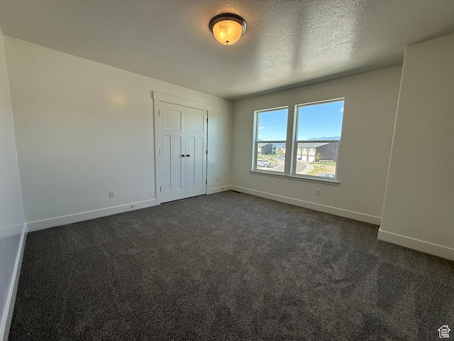 3298 S 1000 W, Nibley, UT 84321 - unfurnished bedroom with dark carpet, a textured ceiling, and a closet