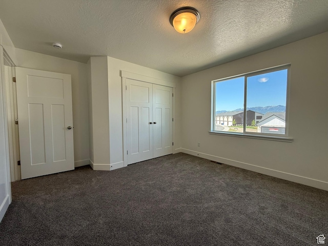 3298 S 1000 W, Nibley, UT 84321 - unfurnished bedroom featuring dark carpet, a textured ceiling, and a closet