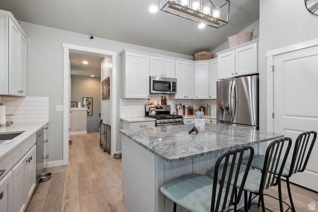 6447 W Arranmore Dr, South Jordan, UT 84009 - kitchen featuring appliances with stainless steel finishes, a kitchen bar, white cabinetry, backsplash, and recessed lighting