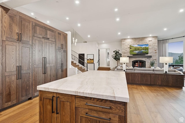 1427 Eagle Way, Park City, UT 84060 - kitchen with light wood-type flooring, a center island, a stone fireplace, light stone countertops, and lofted ceiling