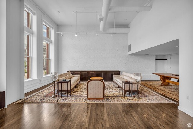 159 W Broadway Unit 301, Salt Lake City, UT 84101 - living room featuring track lighting, wood finished floors, healthy amount of natural light, brick wall, and a towering ceiling