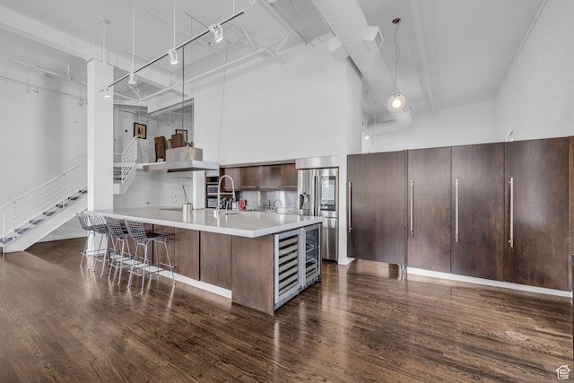 159 W Broadway Unit 301, Salt Lake City, UT 84101 - kitchen featuring stainless steel fridge, light countertops, dark wood-type flooring, a breakfast bar, and a high ceiling