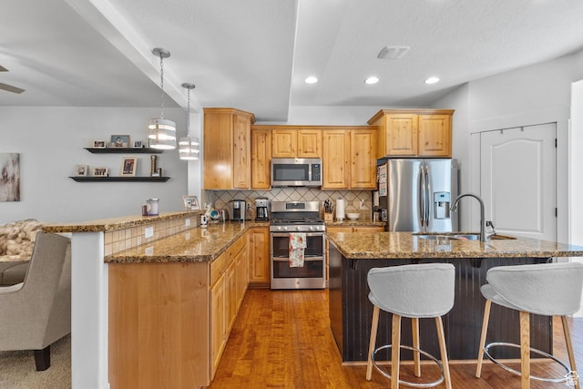 4269 W Lake Brg S, South Jordan, UT 84009 - kitchen featuring stainless steel appliances, stone countertops, a breakfast bar area, decorative backsplash, and a peninsula