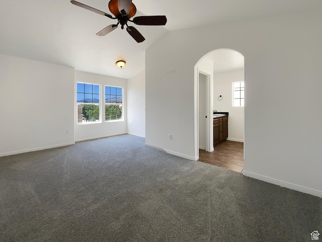 6842 W Grevillea Ln, West Jordan, UT 84081 - tiled spare room featuring arched walkways, ceiling fan, carpet floors, and lofted ceiling