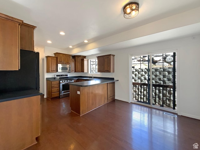 6842 W Grevillea Ln, West Jordan, UT 84081 - kitchen with stainless steel appliances, a peninsula, dark countertops, recessed lighting, and dark wood finished floors