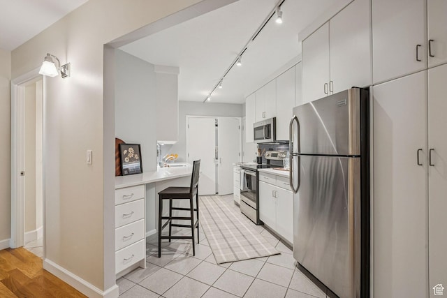 900 S Donner Way E Unit 405, Salt Lake City, UT 84108 - kitchen featuring appliances with stainless steel finishes, track lighting, light countertops, a breakfast bar area, and white cabinets