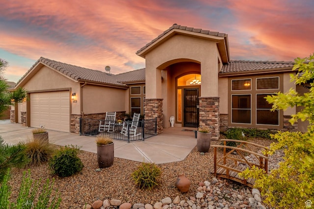 1430 W 365 N, Hurricane, UT 84737 - mediterranean / spanish-style house featuring a tiled roof, stone siding, an attached garage, and concrete driveway