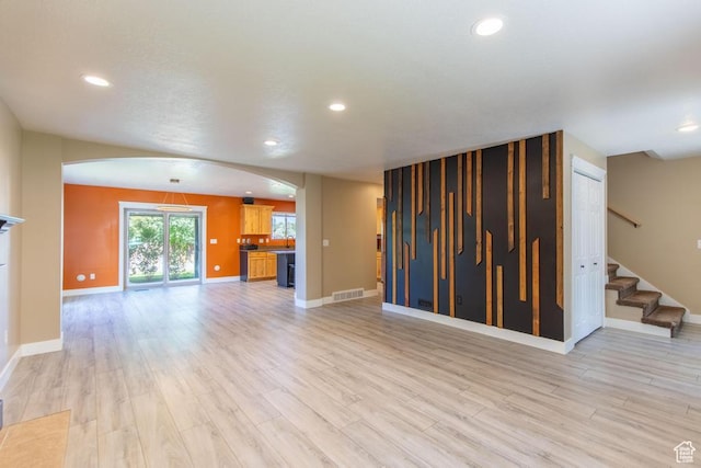 1033 S Southgate Ct W, Logan, UT 84321 - unfurnished living room with arched walkways, light wood finished floors, recessed lighting, and stairs