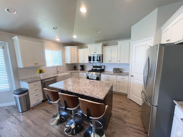 2433 N 1445 W, Clinton, UT 84015 - kitchen with appliances with stainless steel finishes, wood finished floors, decorative backsplash, a kitchen island, and recessed lighting