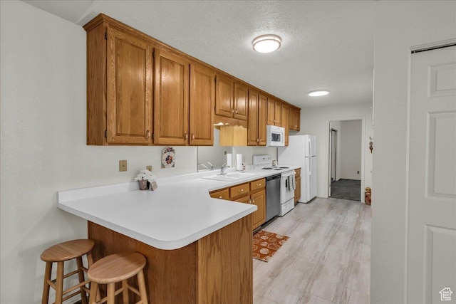 1331 N Dixie Downs Rd Unit 56, St George, UT 84770 - kitchen featuring white appliances, a breakfast bar, brown cabinetry, and a textured ceiling