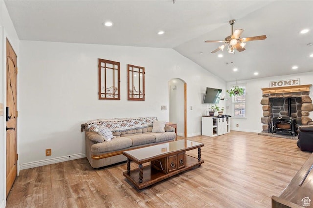 7217 W Mccuiston Ave S, Herriman, UT 84096 - living room featuring arched walkways, ceiling fan, vaulted ceiling, light wood-type flooring, and a wood stove