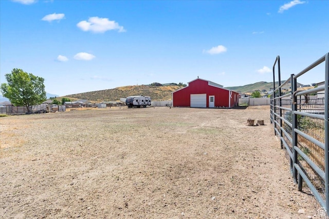 7217 W Mccuiston Ave S, Herriman, UT 84096 - view of yard featuring a detached garage, a mountain view, a pole building, an outdoor structure, and dirt driveway