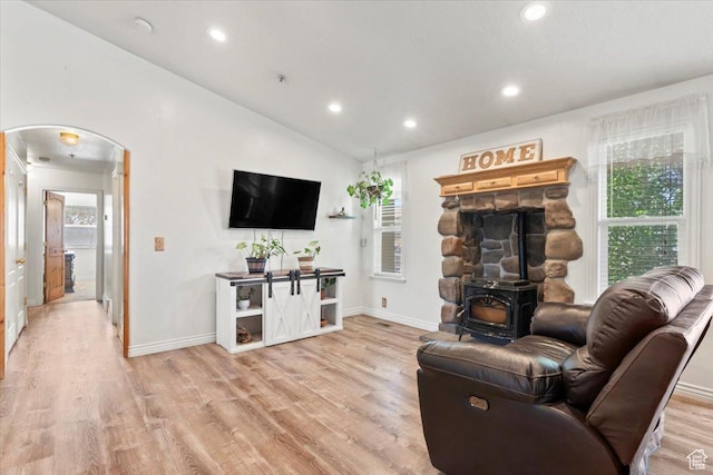 7217 W Mccuiston Ave S, Herriman, UT 84096 - living area featuring arched walkways, light wood-style flooring, lofted ceiling, recessed lighting, and a wood stove
