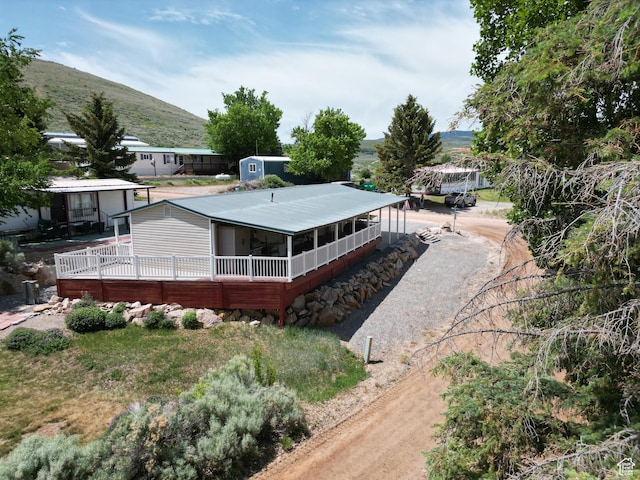 3077 S Edgemont Dr, Garden City, UT 84028 - back of property featuring a sunroom, driveway, and a mountain view