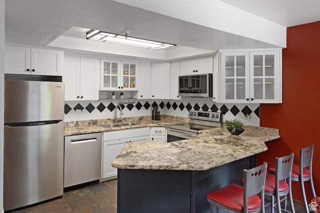 1035 Park Ave Unit 7-G, Park City, UT 84060 - kitchen featuring stainless steel appliances, a peninsula, white cabinetry, and decorative backsplash