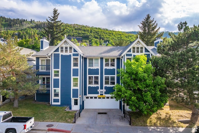 1035 Park Ave Unit 7-G, Park City, UT 84060 - view of front of home with concrete driveway, an attached garage, a chimney, a view of trees, and a front lawn