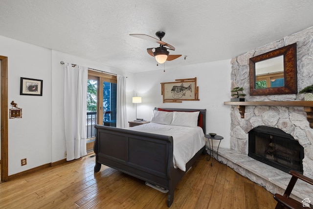 1035 Park Ave Unit 7-G, Park City, UT 84060 - bedroom with access to exterior, a textured ceiling, light wood-type flooring, a stone fireplace, and a ceiling fan