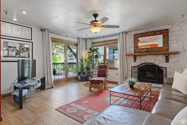 1035 Park Ave Unit 7-G, Park City, UT 84060 - living room featuring hardwood / wood-style flooring, a textured ceiling, a ceiling fan, a stone fireplace, and cooling unit