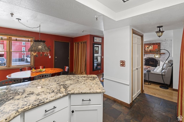 1035 Park Ave Unit 7-G, Park City, UT 84060 - kitchen with white cabinets, light stone countertops, stone tile flooring, and a textured ceiling
