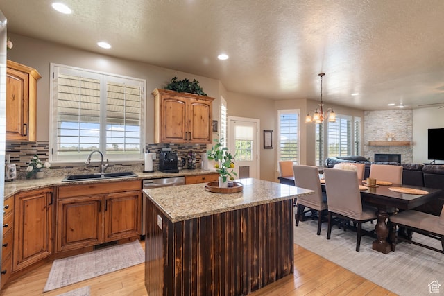 3535 W Overlook Dr, Layton, UT 84041 - kitchen with light wood-type flooring, a textured ceiling, a fireplace, tasteful backsplash, and plenty of natural light