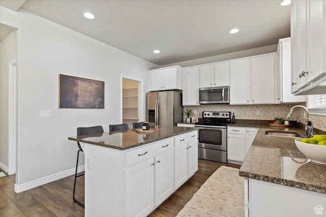 9714 S Oia Ln W, South Jordan, UT 84095 - kitchen with appliances with stainless steel finishes, dark wood-style flooring, a breakfast bar area, backsplash, and dark stone counters