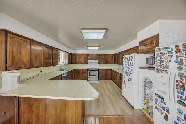 1731 E 1460 N, Logan, UT 84341 - kitchen with appliances with stainless steel finishes, light countertops, a peninsula, light wood finished floors, and a textured ceiling
