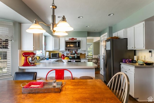 5668 S 1090 W, Murray, UT 84123 - kitchen featuring appliances with stainless steel finishes, white cabinets, a peninsula, light countertops, and decorative light fixtures