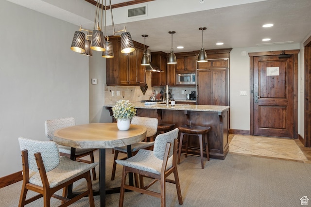 3558 Escala Ct Unit 252, Park City, UT 84098 - kitchen with stainless steel microwave, a peninsula, light stone countertops, backsplash, and decorative light fixtures