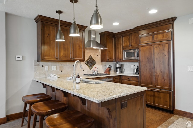 3558 Escala Ct Unit 252, Park City, UT 84098 - kitchen with wall chimney range hood, built in appliances, a peninsula, decorative backsplash, and recessed lighting