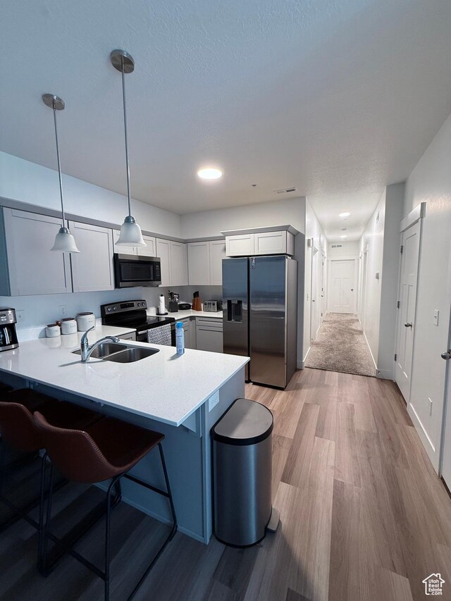 13547 S Hanley Ln Unit 202, Riverton, UT 84096 - kitchen with stainless steel appliances, light wood-style floors, a peninsula, and a kitchen breakfast bar