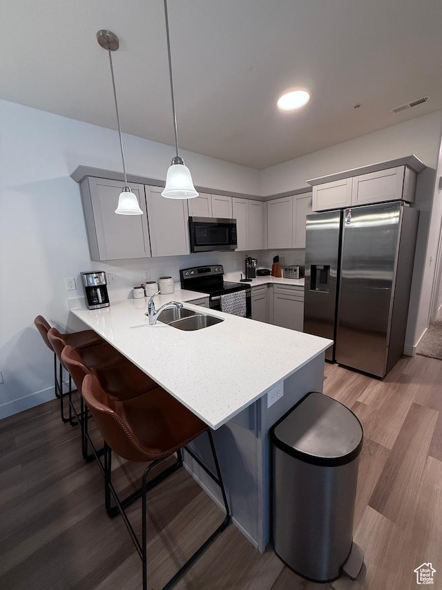 13547 S Hanley Ln Unit 202, Riverton, UT 84096 - kitchen featuring appliances with stainless steel finishes, a peninsula, gray cabinets, a kitchen bar, and light countertops