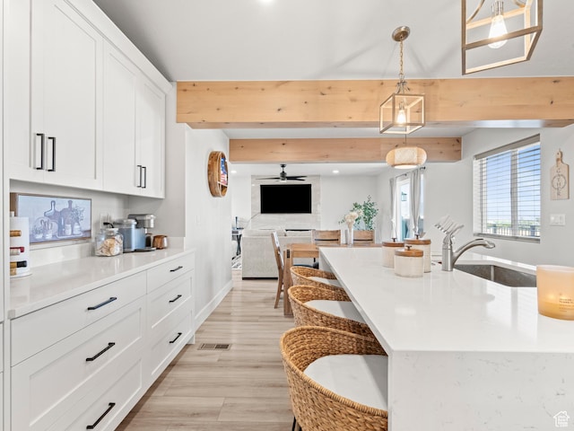 214 S 900 W, Tooele, UT 84074 - kitchen with white cabinetry, beamed ceiling, hanging light fixtures, open floor plan, and a ceiling fan