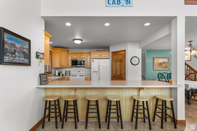 1340 N Trapper Loop, Garden City, UT 84028 - kitchen with white appliances, a peninsula, light countertops, recessed lighting, and a breakfast bar area