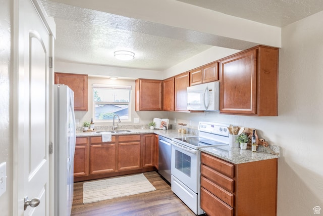 774 W 4375 S, Riverdale, UT 84405 - kitchen with white appliances, a textured ceiling, wood finished floors, brown cabinets, and light stone countertops