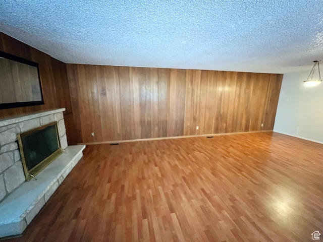399 W 400 N Unit 47, Bountiful, UT 84010 - unfurnished living room featuring a textured ceiling, wood finished floors, a stone fireplace, and wooden walls