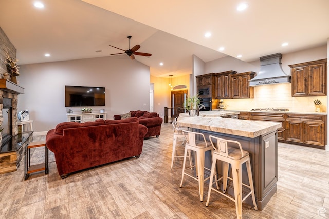 4311 N Diamond Ln, Erda, UT 84074 - kitchen featuring custom exhaust hood, a breakfast bar area, light countertops, a stone fireplace, and a ceiling fan