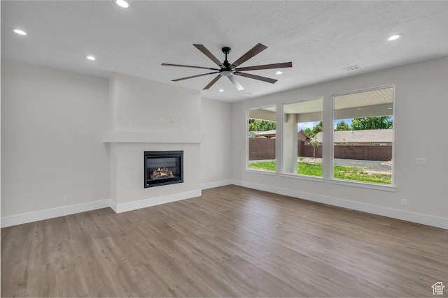 21 W Elinor Ln, Washington, UT 84780 - unfurnished living room with wood finished floors, ceiling fan, recessed lighting, a glass covered fireplace, and a textured ceiling