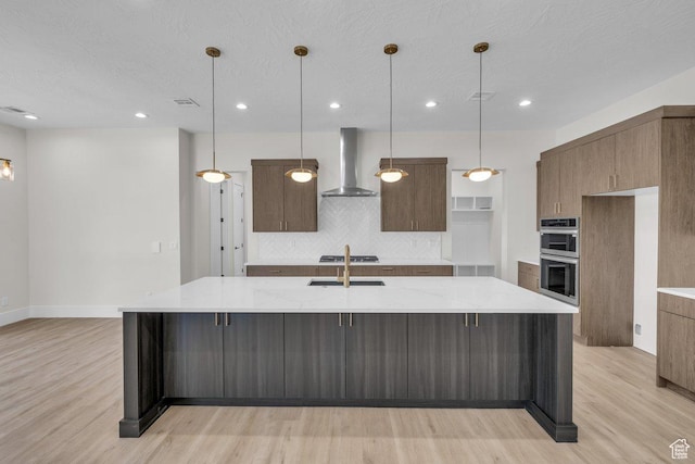 21 W Elinor Ln, Washington, UT 84780 - kitchen featuring wall chimney exhaust hood, stainless steel double oven, light wood-style floors, decorative backsplash, and a large island